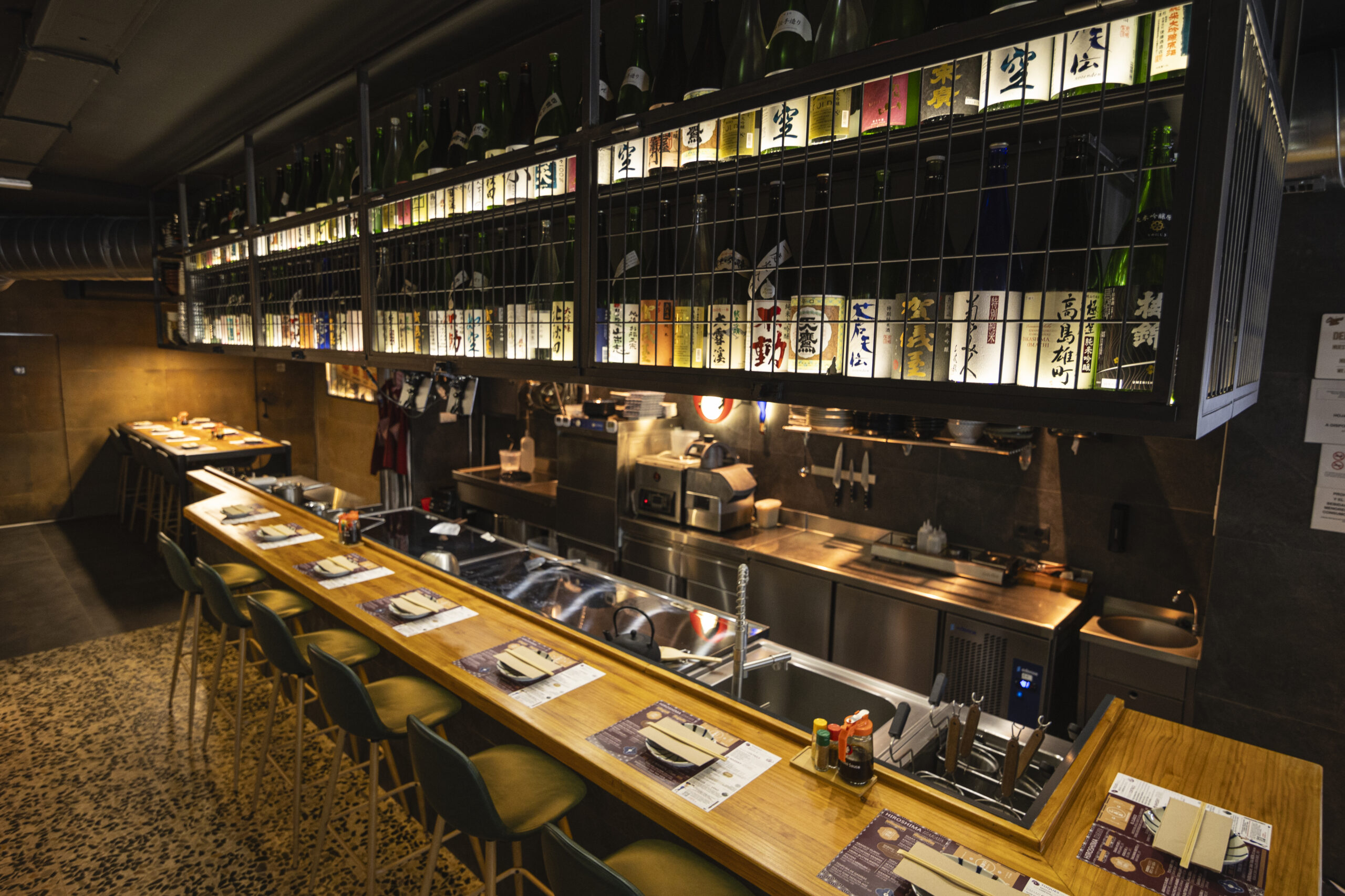 Barra japonesa tradicional y cocina abierta con taburetes en el restaurante Okonomi San en Madrid