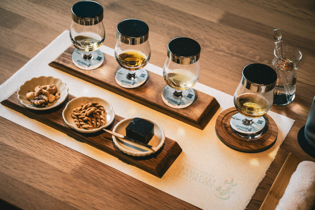 Copas de cata con diferentes whiskies de malta constituyentes para el ensamblaje de Yamazaki 12 sobre una mesa de madera.